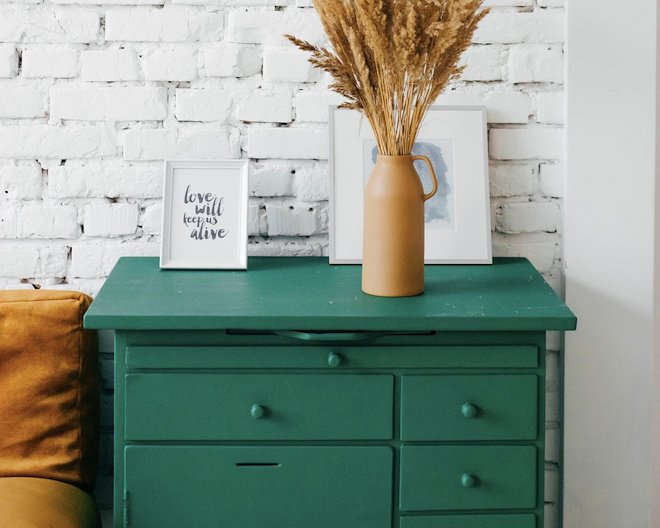Green drawer with pictures and a wheat-filled vessel on top